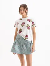Remera blanca de manga corta y cuello redondo, con estampado de peras en tonos rosados y verdes.