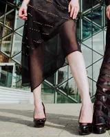 Vestido midi negro en línea A, con corte irregular en chiffon y tajos en los costados. Decorado con perlas doradas, se ajusta con tirantes espagueti cruzados en la espalda. Escotes delantero y trasero pronunciados.