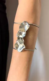 Brazalete plateado para el brazo, hecho a mano en alpaca, con diseño de formas orgánicas irregulares.