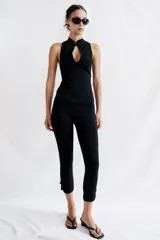 Pantalón capri negro de tiro medio con cintura elástica y detalle de alamares en el bajo.
