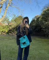 Bolso amplio tipo shopper confeccionado en cuero gamuza de color fucsia, con asas de cuero marrón y un aplique de caballo en pelo natural.