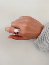 Anillo de acero quirúrgico con diseño circular abierto y piedra central redonda de color blanco.