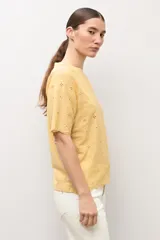 Remera blanca de manga corta con tejido de broderie, cuello redondo y diseño holgado.