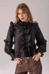 Camisa celeste con volados decorativos en los hombros, pecho, mangas y ruedo, destacados con ribetes en tono rojo. Presenta cierre frontal de botones, cuello alto y mangas largas abullonadas con puños ajustados.