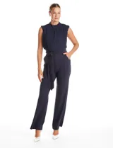 Enterito de crepe color azul marino, con torso plisado sin mangas y cuello alto. Presenta corte en la cintura con lazo de ajuste y pantalón de pierna recta con bolsillos funcionales.