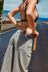 Jean de corte oversize con tiro medio-alto, confeccionado en denim de algodón con lavado tipo ice wash en tono grisáceo. Presenta diseño de cinco bolsillos, cierre frontal y etiqueta de cuero en la parte posterior de la cintura.