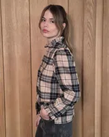 Camisa de algodón con estampado de rayas verticales finas, cuello alto con volados, cierre frontal con botones dobles y mangas largas con puños elásticos terminados en volados.