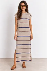 Vestido largo de punto color visón, sin mangas y con cuello redondo, diseño a rayas horizontales en tonos azul, blanco y bordó, y tajos laterales en la falda.
