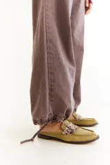 Pantalón de jean de tiro bajo, color marrón con efecto lavado, de corte recto y holgado. Presenta cordones de ajuste en los tobillos para modificar la silueta y bolsillos laterales.