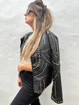 Chaqueta negra de cuero sintético con tachas plateadas, lentejuelas y strass.