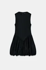 Vestido corto negro sin mangas, con cuello redondo y diseño de falda con volumen tipo globo. Presenta un corte entallado en el torso y cierre de cremallera oculta en la espalda.