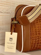 Correa de repuesto para cartera, de tela color beige con rayas blancas y negras. Incluye herrajes metálicos color bronce y apliques de cuero sintético color marrón.