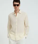 Camisa de manga larga con cuello camisero y abotonadura frontal, confeccionada en una mezcla de lino y algodón. Presenta un diseño liso y minimalista, ideal para un estilo fresco y versátil.