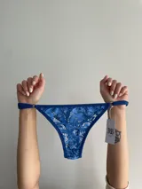 Bombacha de encaje azul con tiras regulables en los costados.