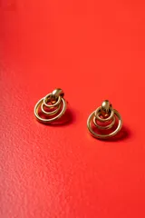 Aros de diseño geométrico formados por tres círculos concéntricos de metal dorado pulido, con cierre de perno.