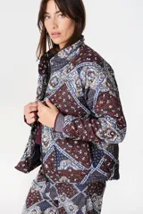 Campera de abrigo capitoneada con diseño estampado, cuello alto y cierre frontal con cremallera y botones a presión. Presenta mangas ranglan y bolsillos laterales.