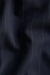 Vestido corto azul marino con finas rayas verticales blancas. Presenta cuello redondo, cierre oculto en la espalda, mangas al codo y una falda con corte circular que genera un efecto volante en el ruedo.