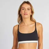 Top de lactancia negro con tirantes ajustables y broches para facilitar la alimentación. Presenta una banda elástica blanca con una línea negra en el borde inferior.