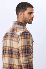 Campera estilo leñadora de viyela a cuadros en tonos beige, marrón y azul, con interior forrado en corderito, cierre frontal con botones y dos bolsillos con solapa en el pecho.