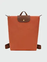 Mochila de diseño minimalista en color beige, con solapa y asa superior en cuero marrón texturizado. Cuenta con correas ajustables en color marrón y cierre principal.