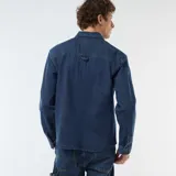 Camisa de denim azul con diseño de rayas verticales finas y blancas, manga larga con puños ajustables, cierre frontal de botones y dos bolsillos de parche con solapa en el pecho.
