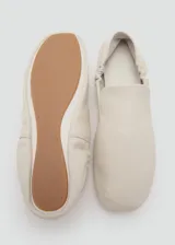 Zapato tipo flat de cuero ovino en color blanco, con diseño de punta redonda y detalle de fruncido elástico en el empeine.