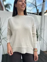 Sweater de tejido de punto color beige, con cuello redondo, mangas largas y puños y ruedo acanalados.