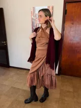 Conjunto de dos piezas color camel compuesto por un top halter cruzado y una falda cruzada con volados en el ruedo. Ambas prendas están confeccionadas en gasa liviana con caída fluida.