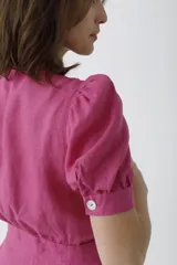 Mono negro de lino con escote pronunciado en V y nudo frontal que deja ver un corte en la cintura. Mangas cortas abullonadas y pantalón de corte recto.