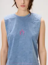 Musculosa crop de algodón con efecto acid wash en color lila, cuello redondo, hombreras marcadas y pequeño bordado central en el pecho.