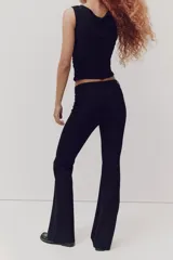 Pantalón sastrero negro de tiro alto, corte ajustado en la parte superior y piernas acampanadas.