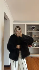 Campera de piel sintética negra, de corte corto y diseño voluminoso con mangas largas.