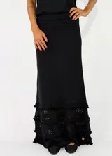Pollera larga de punto color negro, con diseño ajustado en la parte superior y detalles de volados con textura en el ruedo.