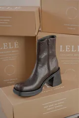 Bota de caña media con punta cuadrada, confeccionada en cuero gamuzado color marrón, con taco bloque y suela de goma negra.