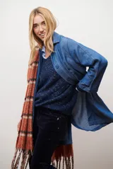 Spolverino largo de jean color azul, con cuello camisero, botones frontales y costuras decorativas en blanco.