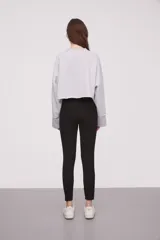 Calza negra de tiro alto con cierre lateral y detalle de costura en la rodilla.