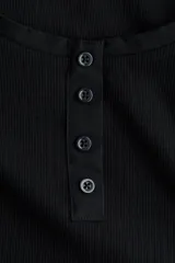 Top entallado de punto acanalado de algodón negro, con manga corta, escote en U y tapeta frontal con botones.