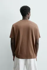 Remera color arena de corte recto, cuello redondo y mangas cortas.