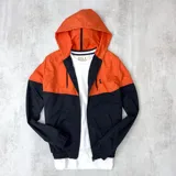 Campera de nylon impermeable con capucha, color naranja en la parte superior y negro en la parte inferior.