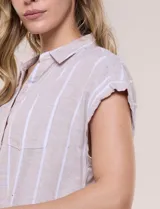 Camisa de lino de estructura recta, color beige con rayas verticales blancas. Cuenta con cuello solapa, escote en V abierto, abotonadura frontal, bolsillo plaqué en el pecho, mangas cortas de hombro caído y ruedo recto.