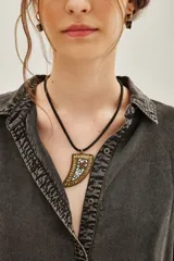 Collar con cordón negro y dije en forma de cuerno, con diseño de escamas en tonos dorados, blancos y rojos.
