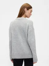 Buzo de punto con cuello en V, manga larga y puños acanalados. Diseño holgado y minimalista.