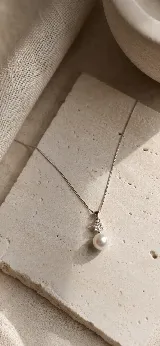 Colgante de plata 925 rodinada con cadena fina, que presenta un dije compuesto por una perla natural de río y una circonia cúbica brillante.