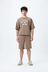 Bermuda marrón de algodón y poliéster, corte relajado, tiro medio, cordón ajustable en la cintura y estampado con inspiración college.