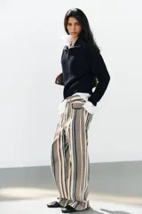 Jeans de tiro medio con diseño de rayas verticales en tonos beige, marrón y verde, corte boyfriend, cinco bolsillos y cierre frontal con cremallera y botón.