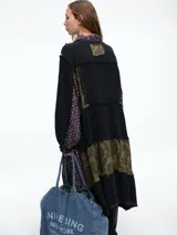 Vestido camisero de corte midi con diseño patchwork que combina paneles en tonos crudo y marrón con estampados florales sutiles. Presenta cierre frontal con botones, cuello camisero y mangas largas con puños.