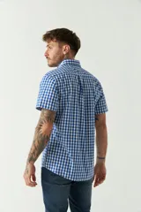 Camisa de manga corta con estampado de cuadros vichy en azul y blanco. Presenta cuello con botones, cierre frontal con botones y logo bordado en el pecho.