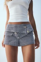 Shorts de tiro bajo a rayas azul marino y blancas, con cinturón ancho decorado con botones metálicos en el frente y bolsillos con solapa.