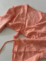 Conjunto de bikini estampado con flores y hojas en tonos rosados, amarillos y verdes. Incluye corpiño con aro y bombacha con lazos laterales.