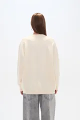 Sweater negro holgado con cuello a la base, manga larga y detalles de mostacillas formando un patrón abstracto.